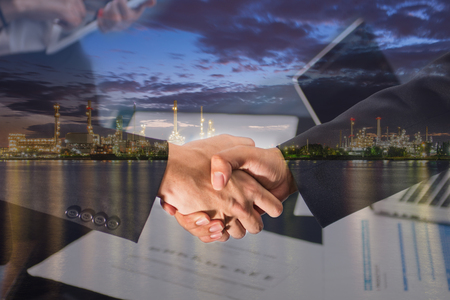 Double Exposure of a businessman handshake on Oil refinery factory in the morning.の写真素材