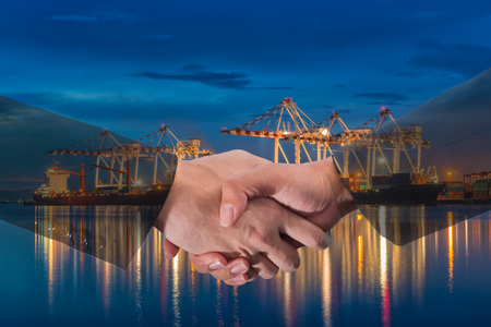 Double Exposure of a businessman handshake on the Industrial port with containers background. Concept of business agreement of industrial port, shipping, transportation, logistic import export.の写真素材