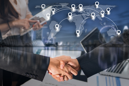 Double exposure of business people handshake greeting deal concept on blue tone of cityscape business district background with map pin flat network conection on world global cartography globalization.の写真素材