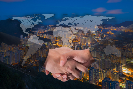 Double Exposure of a businessman handshake on World Global Cartography Globalization with Cityscape Hong Kong Panoramic Night Conceptの写真素材