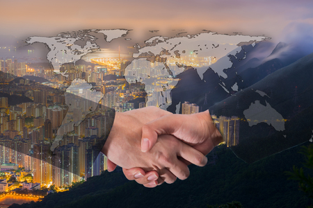 Double Exposure of a businessman handshake on World Global Cartography Globalization with Cityscape Hong Kong Panoramic Night Conceptの写真素材