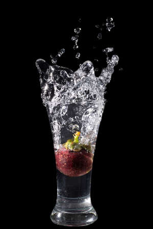 Mangosteen Dropped Into a Glass with a Big Splash , isolated on blackの写真素材