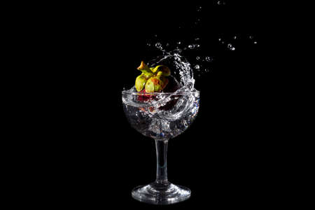 Mangosteen Dropped Into a Glass with a Big Splash , isolated on blackの写真素材