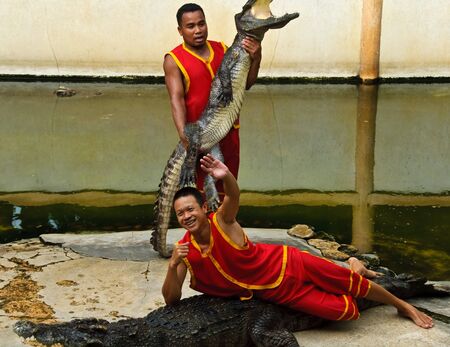 SAMUTPRAKARN, THAILAND - JUNE 11: These men was waving goodbye in a crocodile show at Samutprakarn crocodile farm & zoo June 11, 2010 in Samutprakarn, Thailand.のeditorial素材