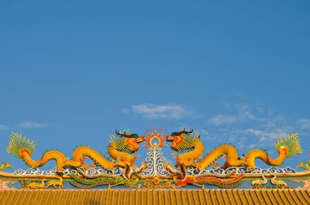 Chinese style dragons on temple's roof over blue sky. Copy space on the top.の写真素材