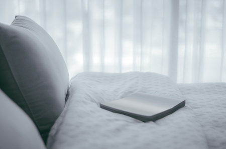 A book situated on the bed with comfortable soft pillowsの写真素材