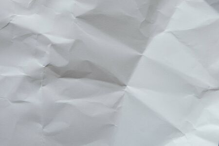 Wrinkled white blank plain paper with shade of light and shadow. Ideal for background or wall wallpaper with copy space for text.の写真素材