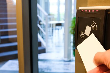 Men hand reaching to use RFID key card to access to office building area and workspace. In building...