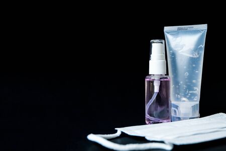 Selective focus of Alcohol gel,spray for hand sanitizer with surgical face mask on black background. Personal hygiene to protect and prevent virus, illness during corona virus out break covid 2019.の写真素材