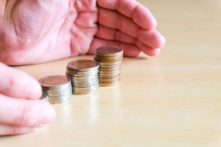Asian men put hands to protect stack of growth money coin. Financial or saving plan for cost reduction, tax or retirement planning, Insurance and personal wealth concept.の写真素材
