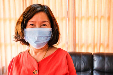 Asian elder women wearing surgical face mask to protect, prevent from Coronavirus  disease.New normal and Social distance concept during pandemic. Personal healthcare concept. With copy space.の写真素材