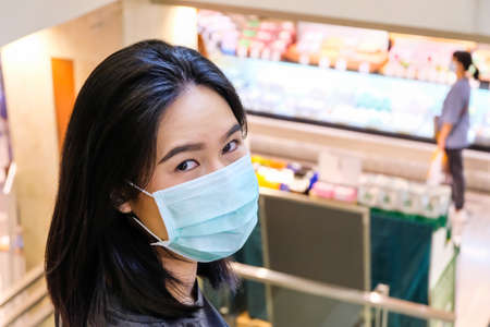 Adult Asian women wearing surgical face mask shopping in department store. New normal, new behavior lifestyle that we need to protect our health from Corona virus. Stay safe and Social distance.の写真素材