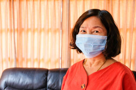 Asian elder women wearing surgical face mask to protect, prevent from Coronavirus  disease.New normal and Social distance concept during pandemic. Personal healthcare concept. With copy space.の写真素材