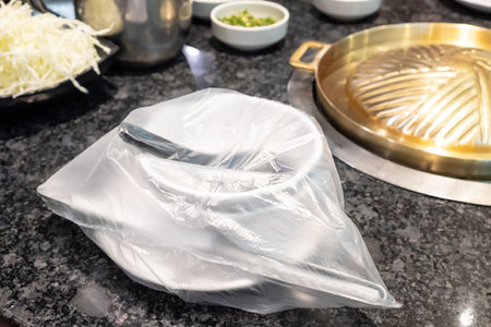 Spoon and dish cover by a plastic at Japanese barbecue grill restaurant. New normal lifestyle that need to sanitize utensil before use. Coronavirus pandemic effect.の写真素材