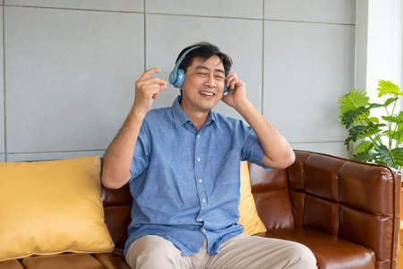 Senior Asian grandfather enjoy and feeling happy while listening music from wireless headphone that streaming music from smartphone or tablet device. Elderly retirement lifestyle with good health.の写真素材