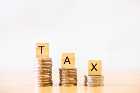 Selective focus at wood tax sign on top of decrease stack of money on the white copy space background. Business or personal tax payment, expense that need to manage and plan.の写真素材