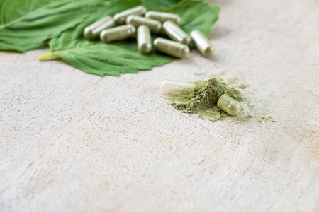 Selective focus at herbal powder. with blurred herb capsule with herbal leaf on natural wooden background with copy space. Alternative medicine that can cure illness without using drugの写真素材