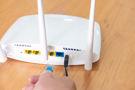 Selective focus at router antenna while men hand connecting fiber cable plug into socket with...