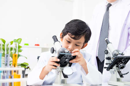 Young Asian element student adjust and using microscope in science class to examine  the lif subject...