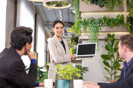 Selective focus at computer screen. Caucasian business women dress in formal suit holding laptop computer while meeting about work project to boss with smile and confident. Banner, indoor shot.の写真素材