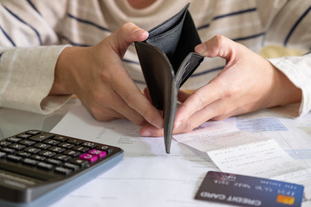 Selective focus at men hand holding open empty wall with no money inside. With blurred invoices and...