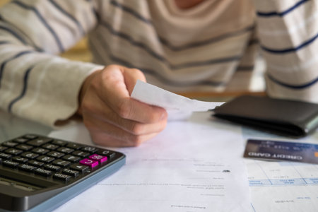 Selective focus at invoice mock up. Close up shot of people who check financial invoice and income statement and use calculator to calculate for personal or credit card expense. Money problemの写真素材