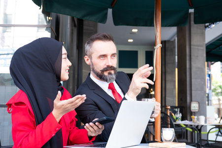Smart business people with formal dress talking and meeting at outdoor coffee shop at business district area. And using laptop computer with smartphone. Diverse working environment with technology.の写真素材