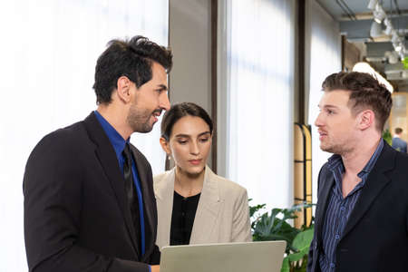 Selective focus at face. Group of multi ethnic business people using laptop, talking and brainstorm inside of the office or modern working space. Corporate meeting and teamwork discussion concept.の写真素材