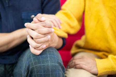 Selective focus at hands. Close up shot of young male homosexual or LGBT couple holding hands and embrace to show love expression. Same gender relationship, love and affection concept.の写真素材