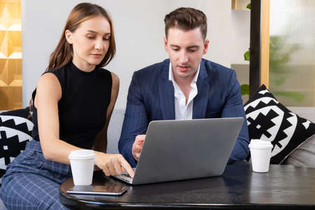 Selective focus at women face. Caucasian business women using computer while meeting and discuss about work project to businessman with smile and confident.  indoor office workspace for casual meetingの写真素材
