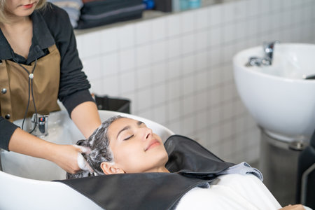 Beautiful Caucasian women feel relax and comfortable while getting hair wash with shampoo and massage. Hair salon studio with hair stylish, beauty and fashion concept.の写真素材