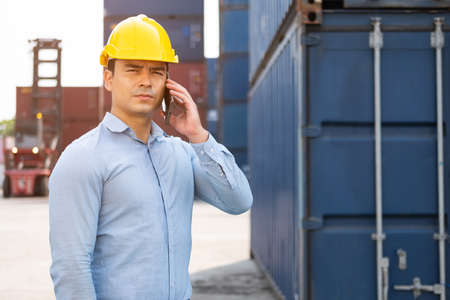 Caucasian men freight supervisor inspect the condition of all containers shipment by using tablet to record data and taking on smartphone. People and worker in freight deliver, import and export.の写真素材