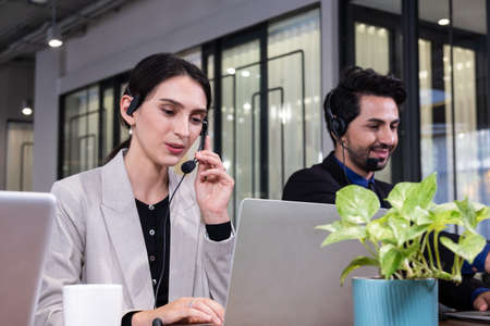 Close up shot of beautiful Caucasian business women with suit formal dress. Using headphone with mic...
