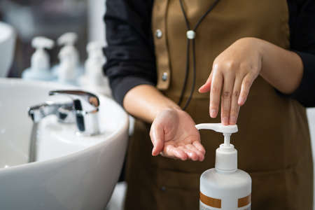 Hand of women hairdresser press on the bottle of shampoo or conditioner before use it to wash customer inside of hair salon studio. Beauty and fashion product and service concept.の素材 [FY310185353244]