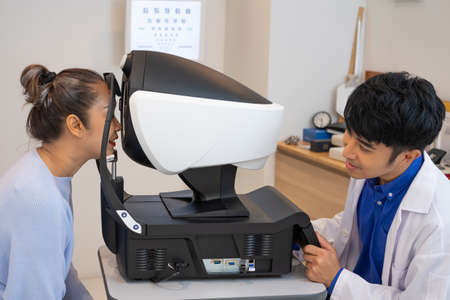 Selective focus at Optometry frame equipment. While doctor using penlight and subjective refraction to  examine eye visual system of elder patient women with professional machine before made glasses.の写真素材