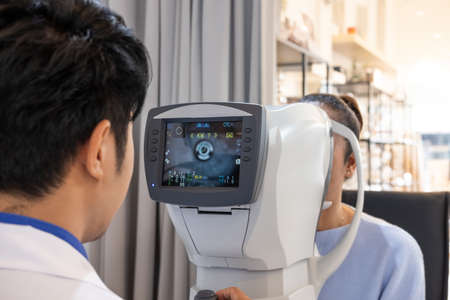 Selective focus at Optometry frame equipment. While doctor using penlight and subjective refraction to  examine eye visual system of elder patient women with professional machine before made glasses.の写真素材