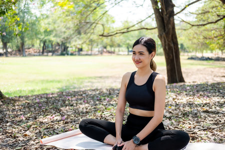 Selective focus at face of young beautiful Asian women smiling while warm up before exercise yoga with natural and trees at background. Healthy lifestyle for good body and health condition.の写真素材