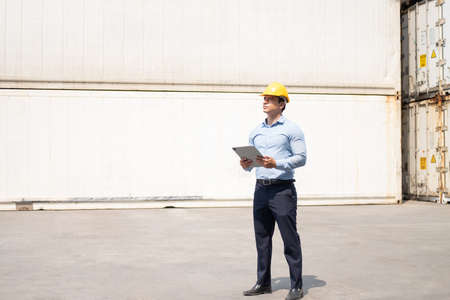 Caucasian men freight supervisor inspect the condition of all containers shipment by using tablet to...