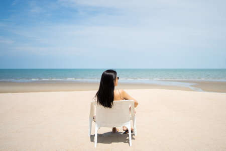 Young women chill out and sitting by the sea beach to get the sun tan with amazing view. Tropical travel vacation or holiday destination concept. Relaxation destination with copy space.の写真素材