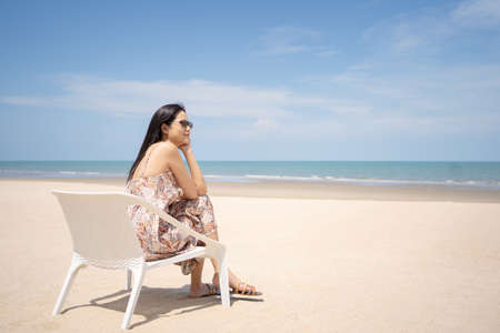 Young women chill out and sitting by the sea beach to get the sun tan with amazing view. Tropical travel vacation or holiday destination concept. Relaxation destination with copy space.の写真素材