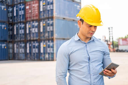 Caucasian men freight supervisor inspect the condition of all containers shipment by using tablet to...