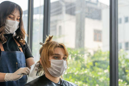 Selective focus at liquid hair color of Hair stylish while hairdressing and put care treatment while styling curly hair for client.の写真素材