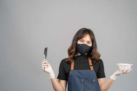 Portrait of Hair stylish holding liquid hair color prepare for hairdressing and put care treatment while styling curly hair for client. Service occupation, beauty and fashionの写真素材