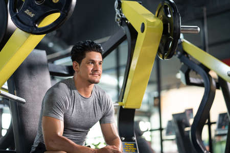 Caucasian men wearing sport cloth and sit inside of indoor fitness gym which has many weight training machine. Workout sport activity, man body and muscle building for healthy lifestyle.の写真素材