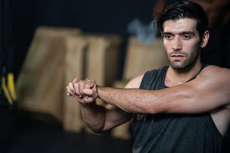 Handsome adult Caucasian men warm up and stretching before do crossfit exercise inside of fitness gym to workout for body strength and firm arms muscle and good physical body health.の写真素材