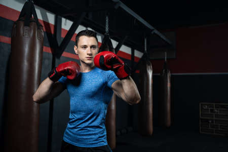 à¹Handsome Caucasian men boxer with strong muscle training boxing punch in side of the gym with sandbag. Cardio sport workout activity for good health and build up body and physical strength.の写真素材
