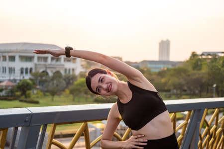 Selective focus at face of young beautiful Asian women wearing surgical face mask while stretching warm up before exercise or running at the park in the morning. New normal lifestyle.の写真素材