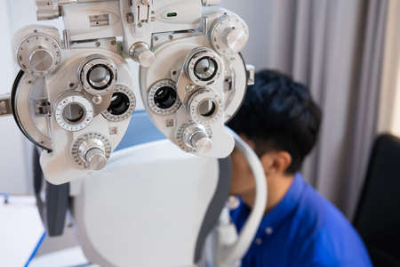 Selective focus at Optometrist face. While doctor using medical equipment and subjective refraction to  examine eye visual system of elder patient women with professional machine before made glasses.の写真素材