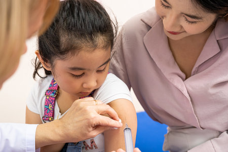 Young Asian girl get medical vaccine injection from the doctor with her mother sit and hold to support. Medical service for young people, kids.の写真素材