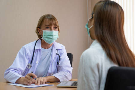 Doctor wearing surgical face mask while doing medical for patient inside of the hospital. Medical service check up.の写真素材
